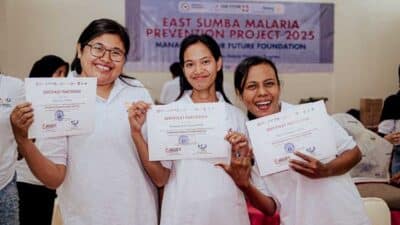 Laboratory analysts certified in East Sumba » The Fair Future Foundation Three female laboratory analysts in white shirts smiling and holding certificates, with a banner reading East Sumba Malaria Prevention Project 2025 in the background.