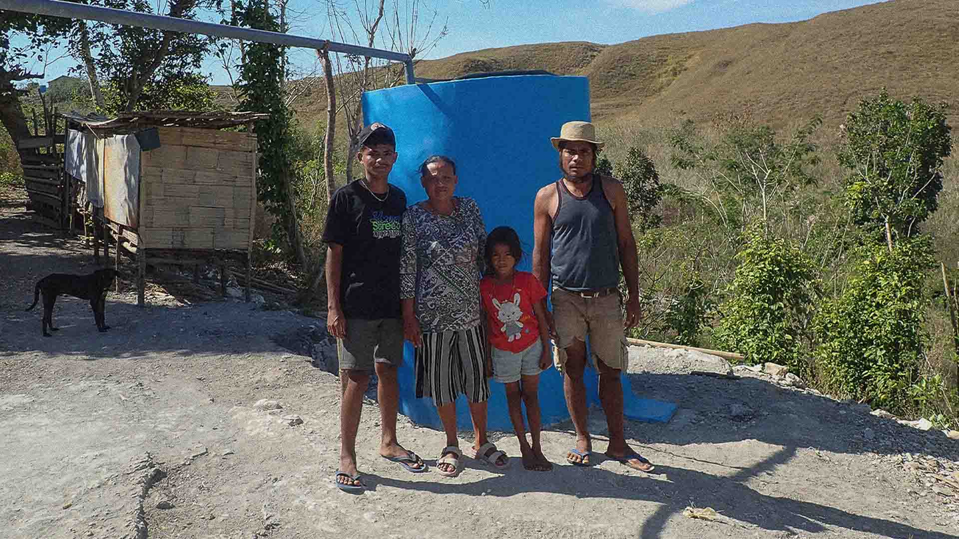 Blue rainwater tank Wai La Padang beside Hambarita homes in East Sumba