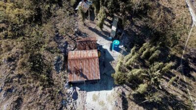Aerial view of Wai La Padang rainwater tank beside two small houses on a rocky hill in Hambarita East Sumba.