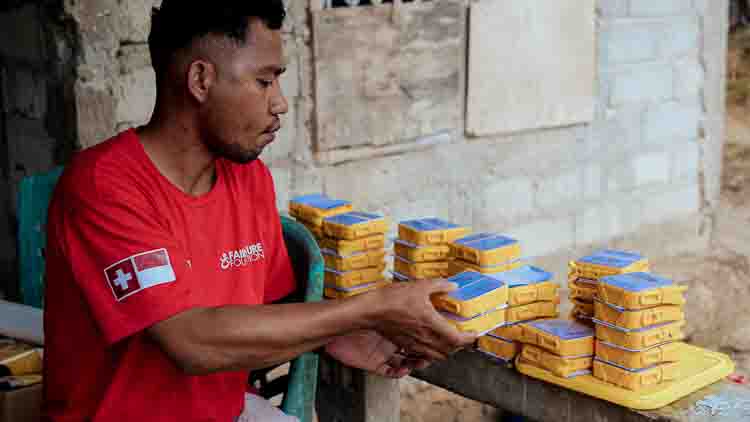 Primus organizes Solharmony lamps on a table after a long journey to a remote East Sumba school.