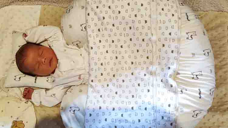 Newborn baby Sorai sleeping peacefully on a patterned blanket, shortly after birth.