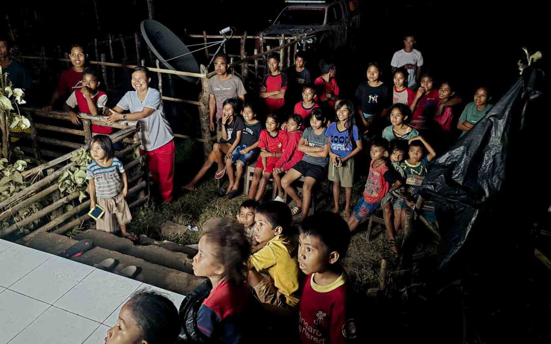 Children and villagers in Mbajik watching a film at night, powered by solar electricity installed at their school for the first time.