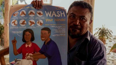 Health center director holding hand hygiene poster in rural Indonesia