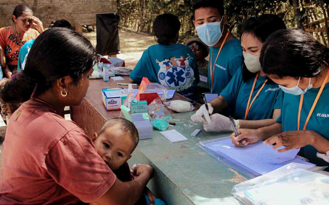 Malaria screening rural Indonesia with medical teams testing a child and educating the mother