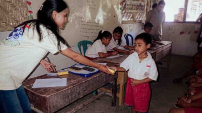 Un collaborateur de Fair Future distribue une SolarBuddy lampe à un jeune élève dans une classe d’école ultra-rurale dans l’est de Sumbawa, en Indonésie.