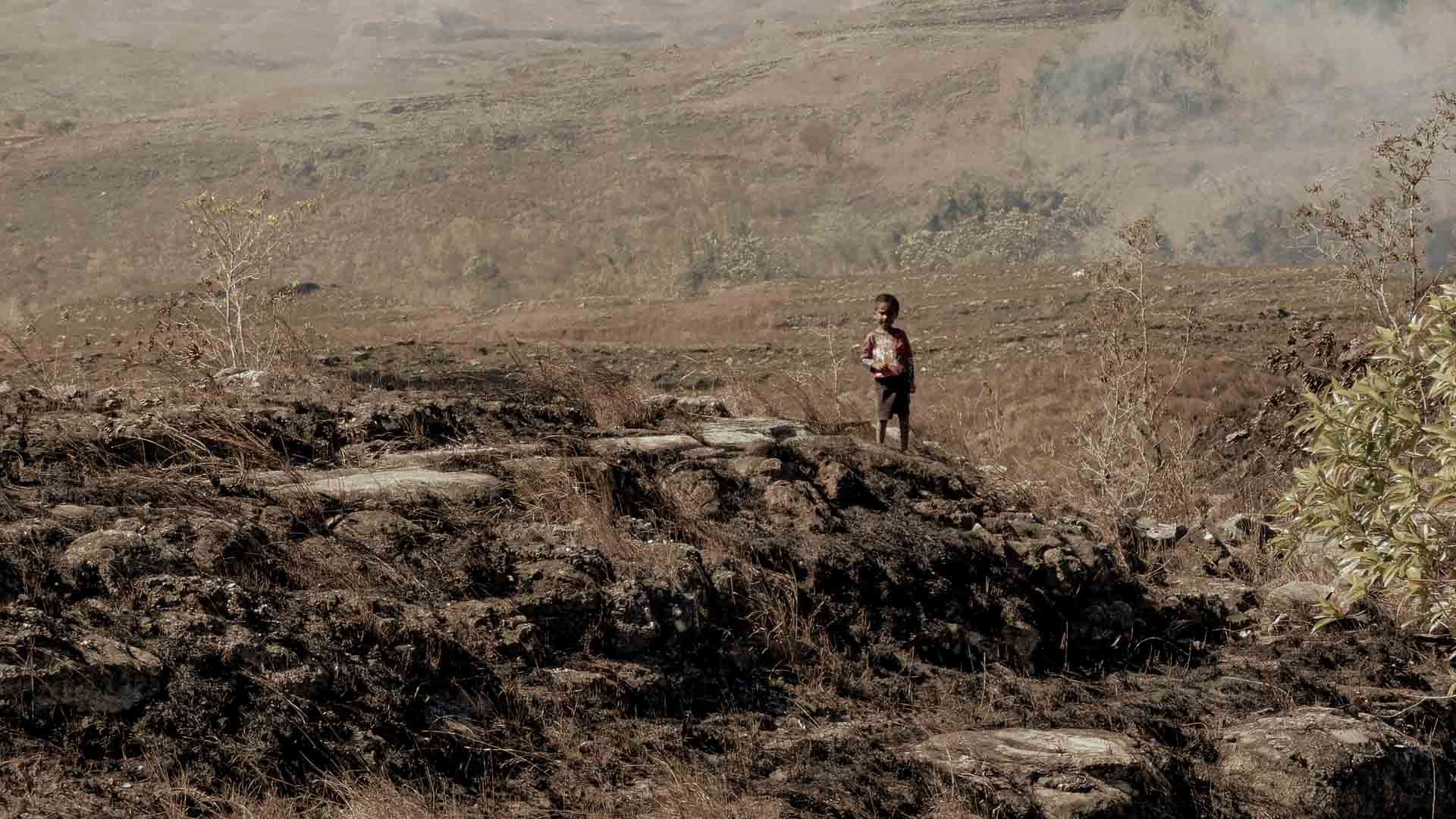 Child walking in an extremely dry landscape affected by extreme heat and water scarcity in an ultra-rural area.