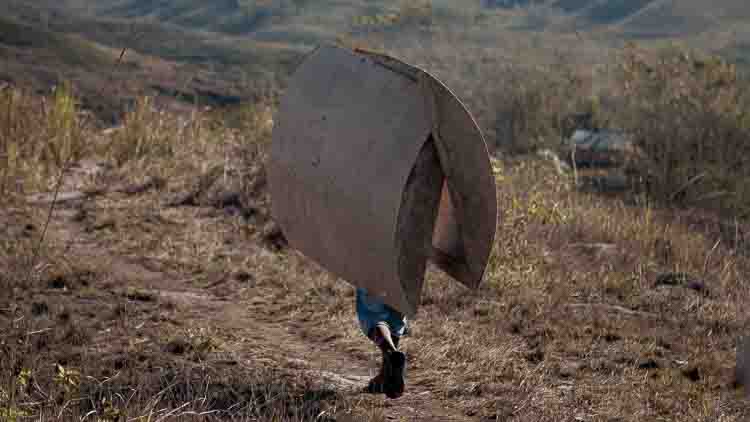 A man walks along a rural path carrying a mold used for the construction of a 5,000-litre water tank in a remote village in East Sumba.