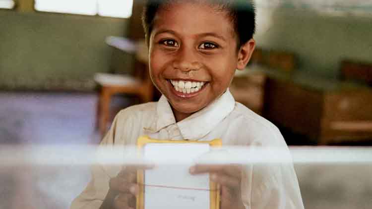 Un enfant reçoit une lampe solaire SolarBuddy dans une école située dans une zone rurale isolée, sans électricité.