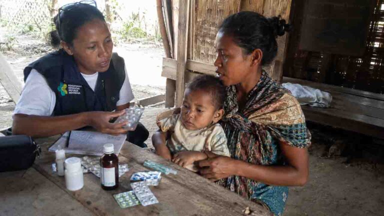 Health worker explaining safe medicine use to a mother and child in rural Indonesia