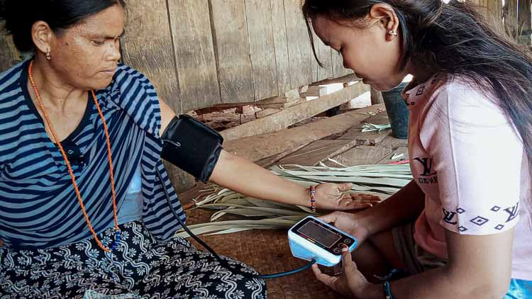 Young Kawan Sehat health agent Atika checks a woman’s blood pressure during a home consultation in Mbatapuhu, East Sumba.