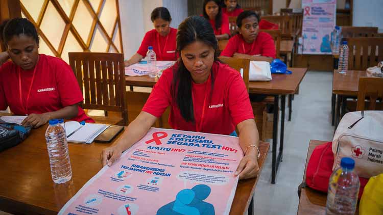 Kawan Sehat health agent Mira studying an HIV prevention and testing poster during training in East Sumba