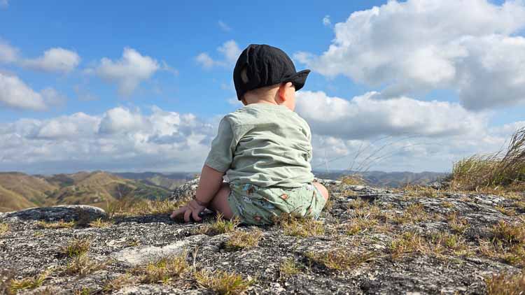 Seven-month-old Sorai sitting on a rocky hill and looking across the dry rural landscape of East Sumba, Indonesia.