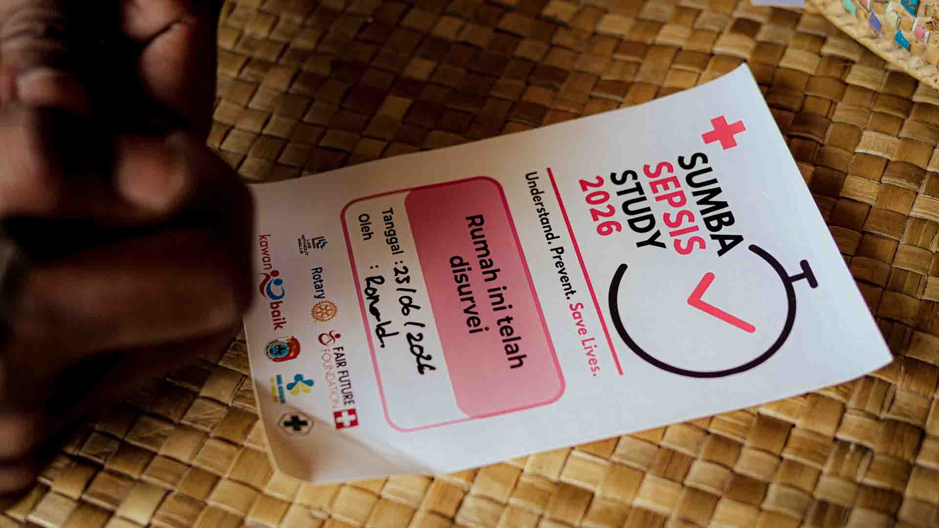 East Sumba Sepsis Study survey sticker on a woven bamboo wall after a household visit