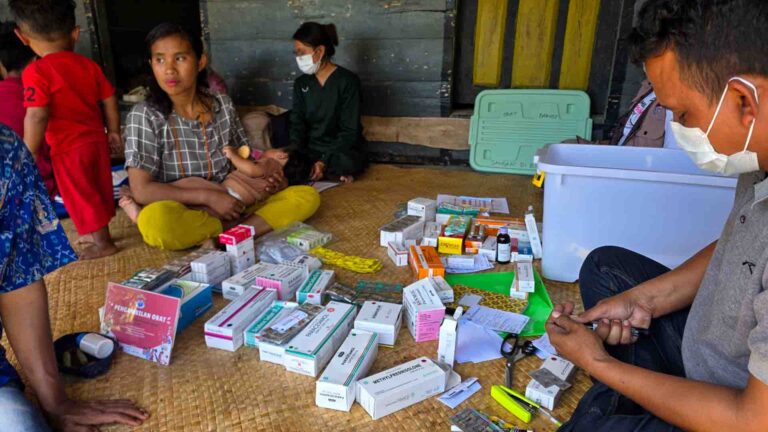 Doctor providing rural healthcare to a woman in Madutolung, East Sumba, with medicines prepared nearby.