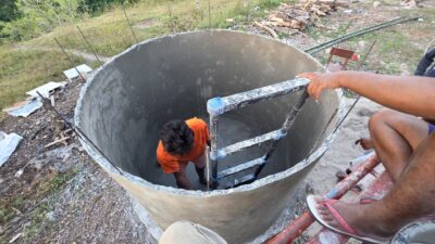 Workers apply a waterproof cement layer inside a ferrocement reservoir under construction in East Sumba.