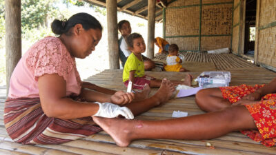 Kawan Sehat l’agente sanitario che cura una ferita alla gamba durante una visita domiciliare nell’East Sumba