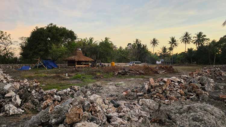 Rumah Kambera 2.0 construction site in East Sumba with stonework, cleared land and the first wooden building.