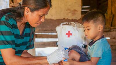 Kawan Sehat agent Veronika treats a child’s wound inside a rural home.