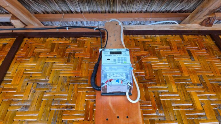Un compteur d'électricité monté sur un mur en bambou tissé à l'intérieur du chantier de Rumah Kambera construction à lopo