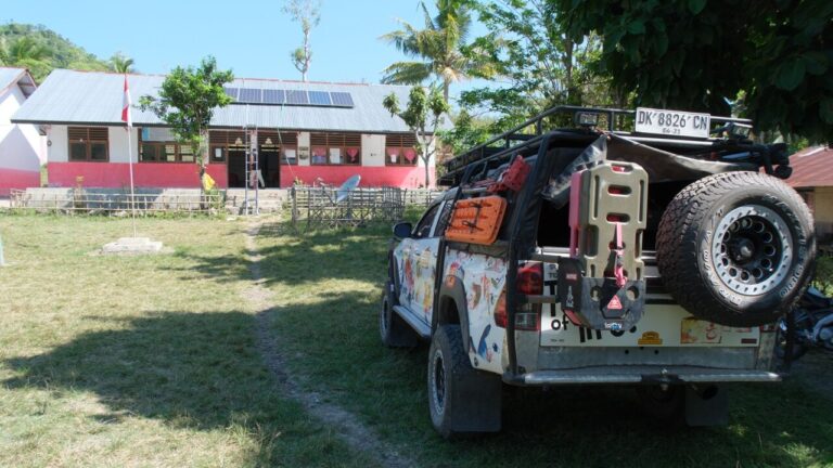 Fair Future Foundation Le véhicule de l'école se trouve à l'extérieur SDN Mbajik, avec des panneaux solaires visibles sur le toit de l'école.