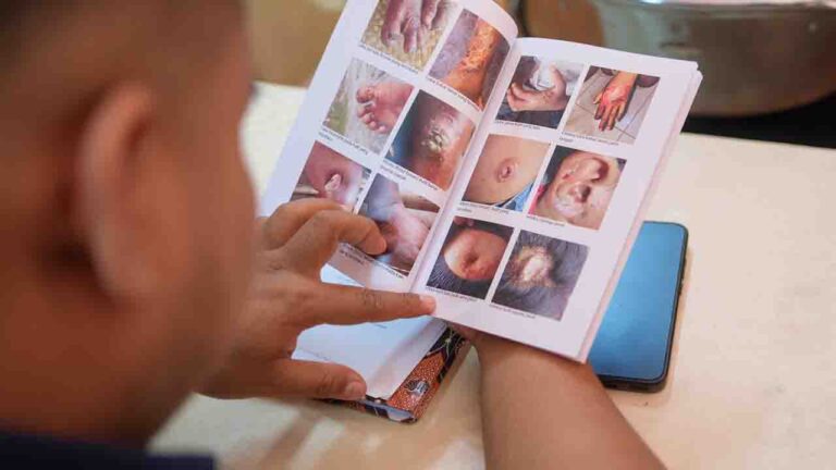 Un professionnel de la santé explique un guide santé illustré à un résident lors de la Sumba Sepsis Study.
