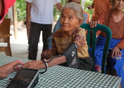 An older woman has her blood pressure measured while another woman stands behind her.