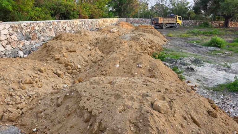 Sirtu Stau am Rumah Kambera Ort Eine Reihe von leeren Behältern im sirtu Inneren der Steinmauer am Ort Rumah Kambera, mit einem Strohdach als Hintergrund.