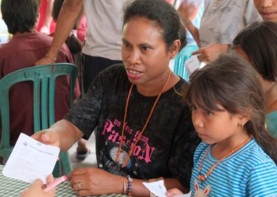 A woman holds out a consultation form across a table, with a girl in a blue striped shirt standing beside her.