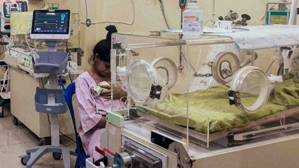 15 year old adolescent mother holding premature baby in rural Indonesia hospital with limited neonatal care