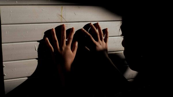 person in shadow hands on wall representing silent STI burden rural Indonesia