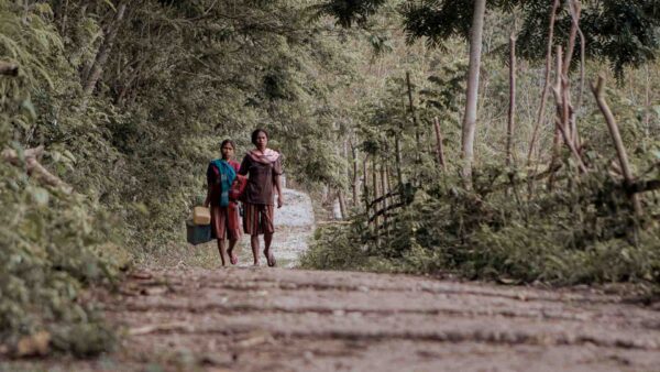 Women walking long rural road in East Sumba showing healthcare access delay