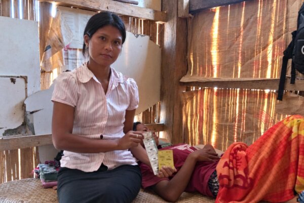 Rambu Esther tient des médicaments près d'une femme qui reçoit des soins de santé communautaires à domicile dans l'est de Sumba.