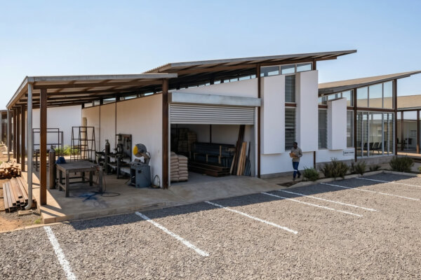 Architectural rendering of the planned workshop and service-bay side of Rumah Kambera 2.0, with outdoor work space and parking.